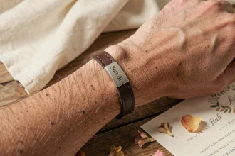 Bracelet en cuir homme personnalisé avec plaque gravée posé sur une table en bois lors d'une préparation de mariage
