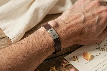 Bracelet en cuir homme personnalisé avec plaque gravée posé sur une table en bois lors d'une préparation de mariage