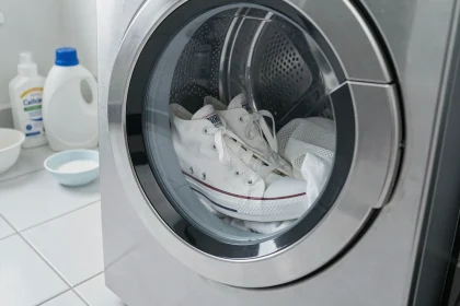 Baskets Converse blanches placées dans un tambour de machine à laver avec un filet de lavage, prêtes pour un lavage délicat